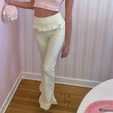 Person wearing light-colored pants with ruffled details in a room with pink walls and wooden floor.